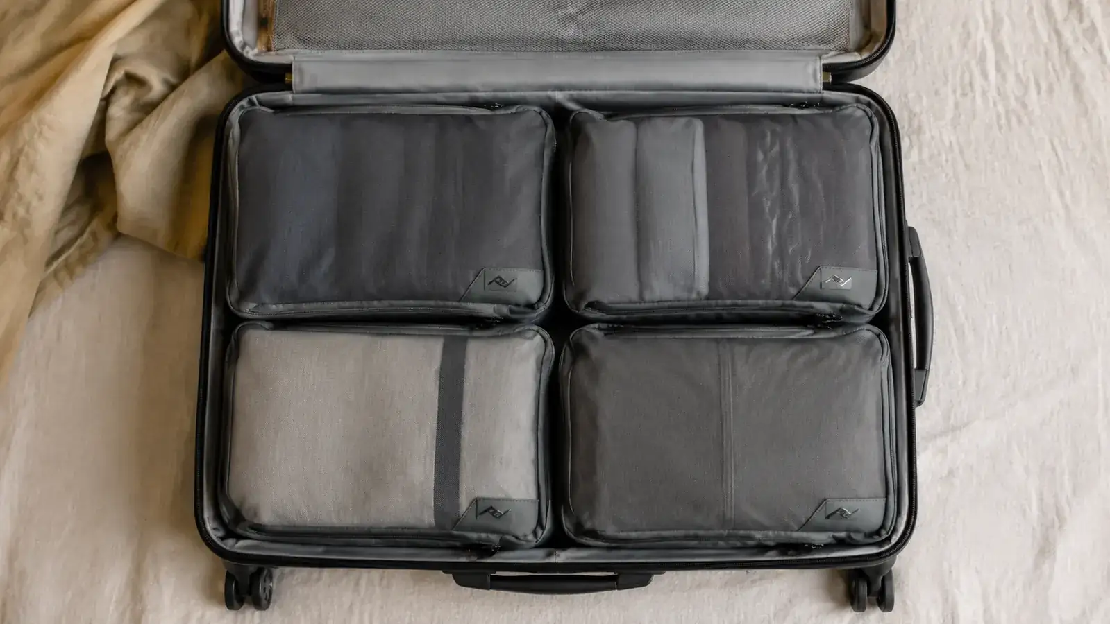 Open carry-on suitcase packed neatly with four flat compression cubes fitting side by side inside the main compartment