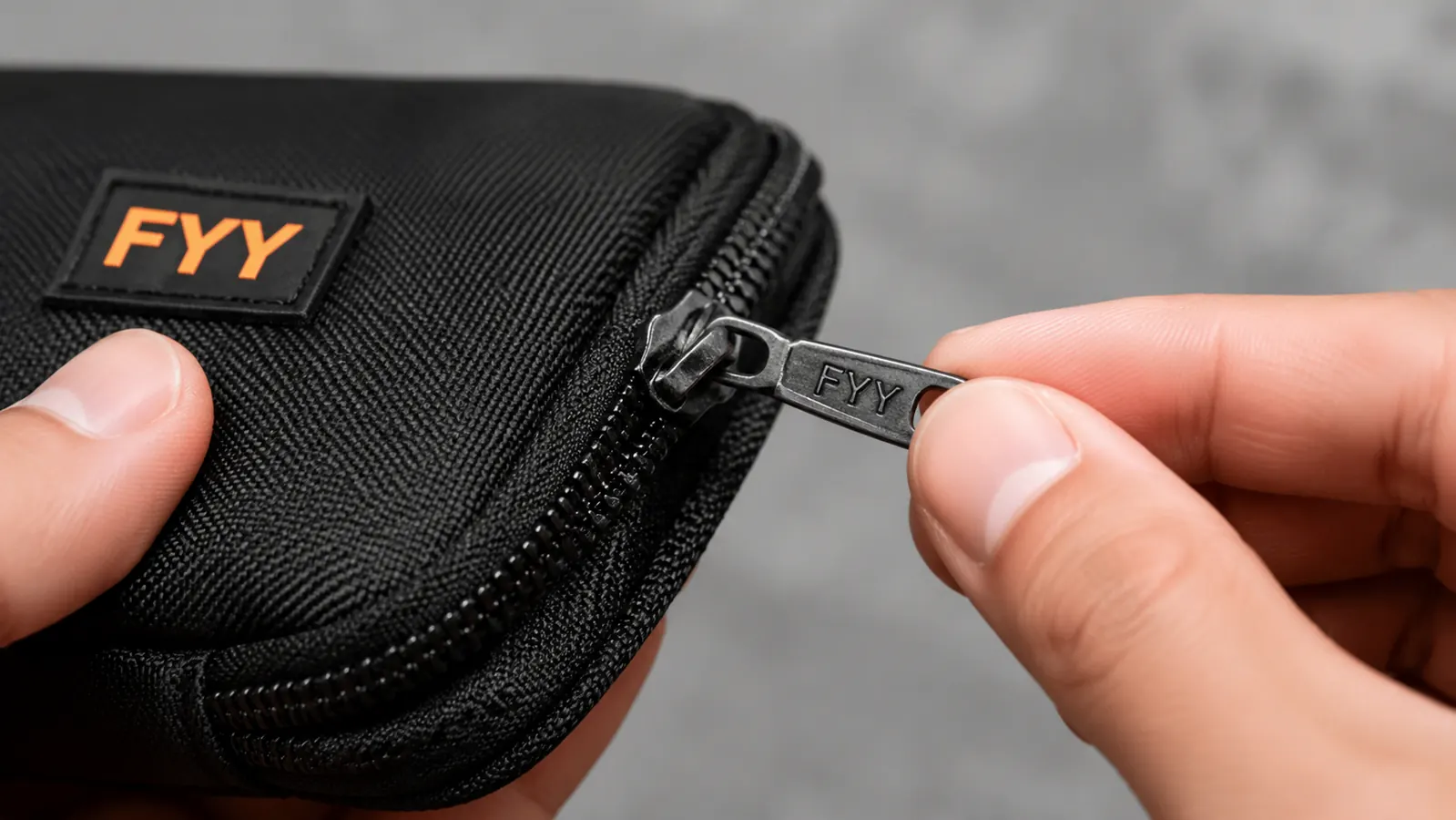 Close-up of a cable organizer zipper pull showing slight wear on the pull tab after a year of regular use