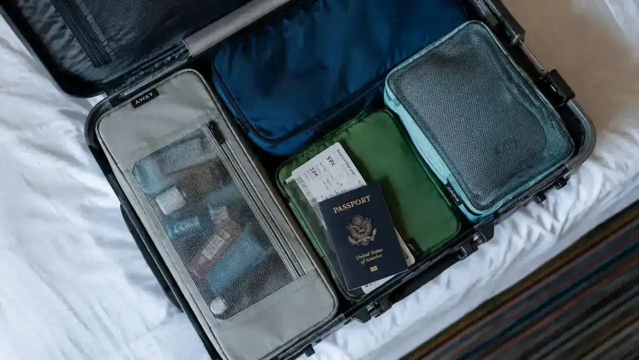 A hanging toiletry bag laid flat in an open carry-on suitcase alongside packing cubes