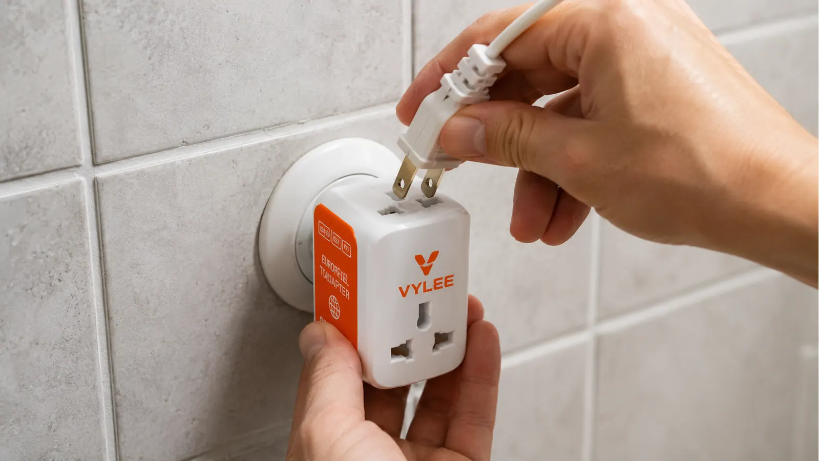 Hand inserting a US plug into the VYLEE travel adapter while it sits in a European Type-C wall outlet